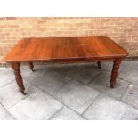 A VICTORIAN WALNUT EXTENDING DINING TABLE with canted corners on turned and fluted supports with