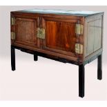 A CHINESE BRASS BOUND ROSEWOOD CABINET on conforming stand with carved decoration, 127cm wide 60cm