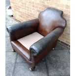 A LARGE CLUB ARMCHAIR with shaped back and outscrolled arms on turned wooden feet and casters,