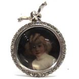 AN EDWARDIAN PASTE SET PICTURE PENDANT in unmarked silver, with paste set ribbon bow bail