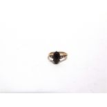 A GARNET AND PEARL THREE STONE RING unmarked, the cabochon flanked by an untested and unwarranted