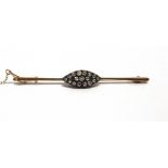 A DIAMOND CLUSTER BAR BROOCH stamped '18ct', the seventeen old cut diamond silver set to a navette