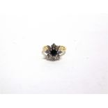 A SAPPHIRE AND DIAMOND 18 CARAT GOLD CLUSTER RING the round cut stone enclosed by eight single cuts,