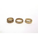 A 9 CARAT GOLD PLAIN WEDDING RING and two patterned 9 carat gold wedding rings