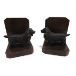 A PAIR OF OAK BOOKENDS circa 1930s, each mounted with a painted cast spelter figure of a spaniel,