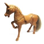 A CARVED WOOD FIGURE OF A HORSE a front leg raised and with horse hair tail, the underside