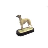 A BORDER FINE ARTS FIGURE OF A STANDING BRINDLE GREYHOUND raised on a polished wooden base, 19cm