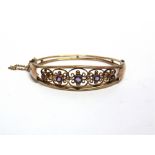 AN EDWARDIAN FIVE STONE AMETHYST HINGED BANGLE the graduated amethysts in wirework settings,