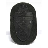 A GERMAN THIRD REICH DEMJANSK SHIELD on its cloth backing.