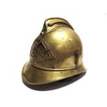 A FRENCH BRASS FIREMAN'S HELMET of regulation pattern, bearing a pierced St. Jean Le Vieux (Pyrennes