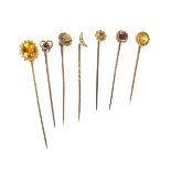 Group of seven yellow gold stick pins.