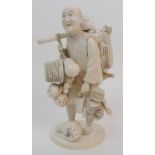 A Japanese ivory okimono of a basket seller standing and carrying various baskets, red seal mark