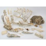 A group of marine ivory carvings comprising; figure in canoe, sleds, tiki figures, seals etc (a lot)