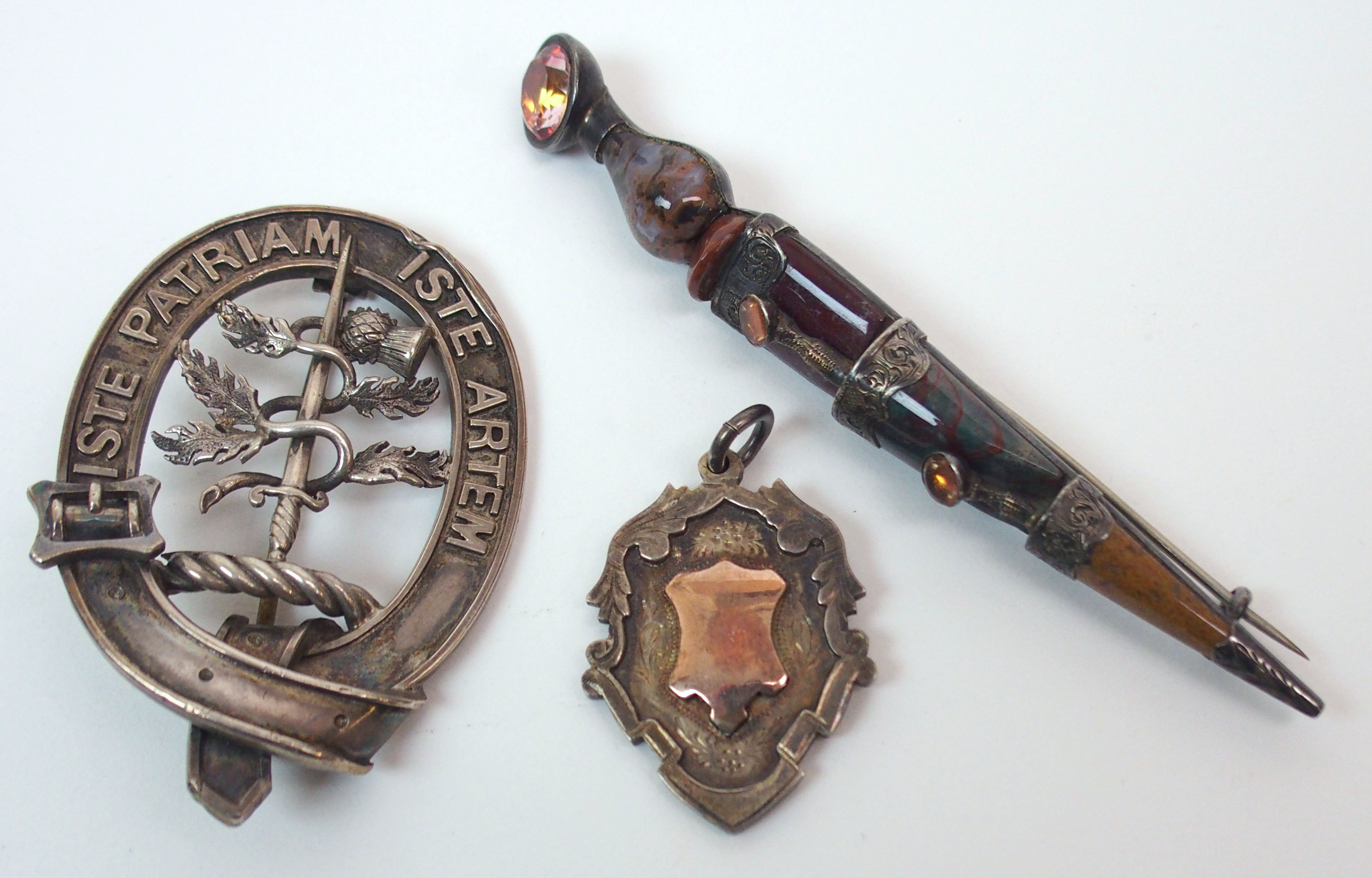 A Victorian Scottish agate kilt pin modelled as a dirk, with a white metal clan badge 'Iste Patriam,