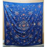 A CHINESE SILK THROW embroidered with baskets of flowers, bats and scattered foliage on a blue