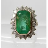 AN EMERALD AND DIAMOND DRESS RING set throughout in white metal with looped shoulders, dimensions of