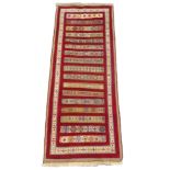 A RED GROUND SOZANI RUG with geometric strips and border, 230cm x 84cm Condition Report: Available