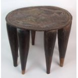 AN AFRICAN HARDWOOD CIRCULAR STOOL the seat carved with geometric patterns and on ten tapering