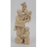 A JAPANESE IVORY OKIMONO carved with a man holding two Oni above a child beating a drum (with some