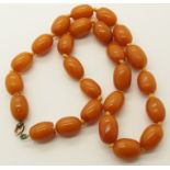 A STRING OF AMBER COLOURED BEADS length 46.5cm, largest bead 1.6cm, smallest 1.4cm, weight 30gms