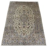 A CREAM GROUND KASHAN RUG with floral designs, central medallion and a border with floral palmettes,