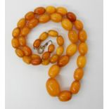 A STRING OF AMBER COLOURED BEADS largest bead, 18.4mm x 13.5mm, smallest 8.8mm x 6.6mm, length of