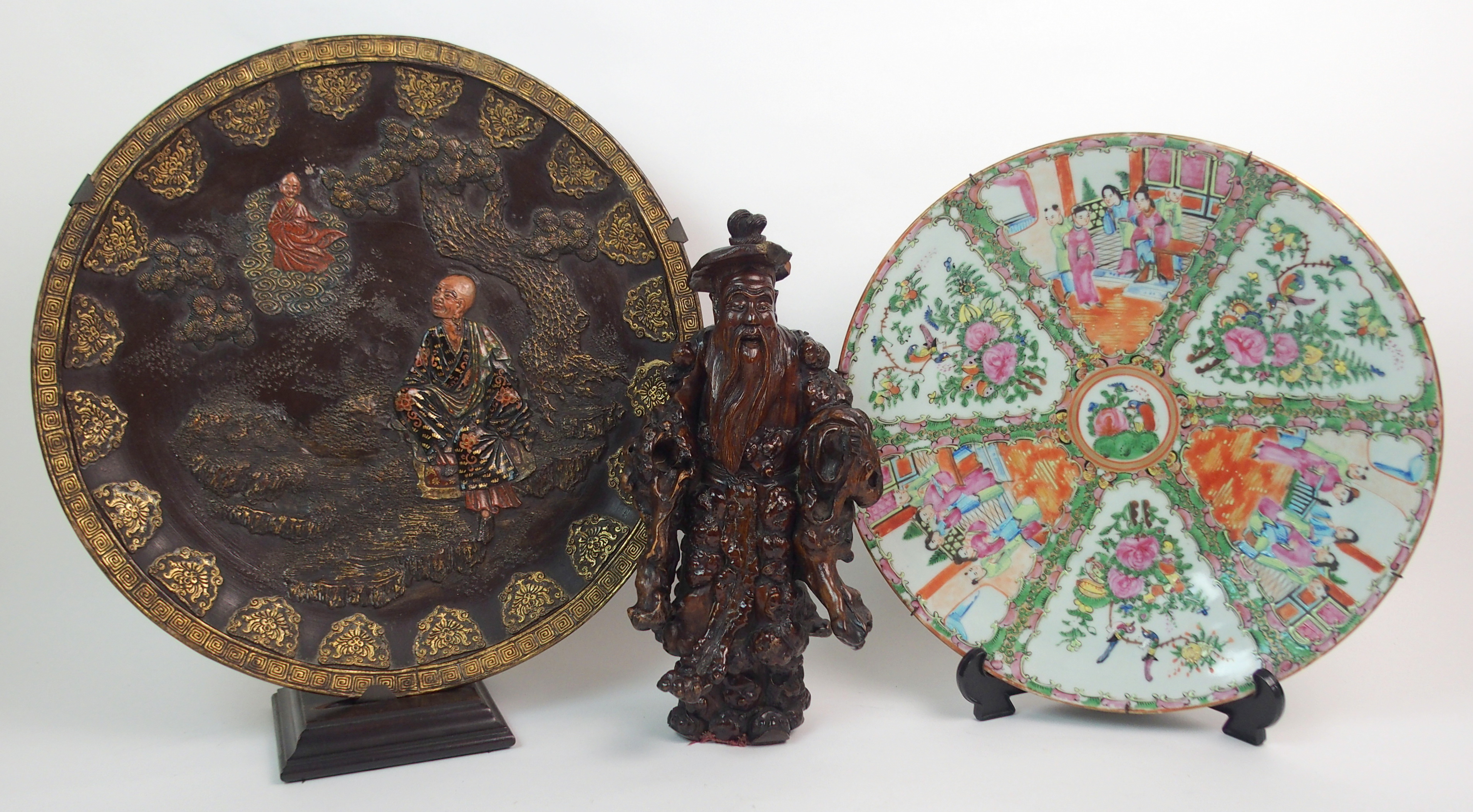 A JAPANESE POTTERY DISH in the Komai style moulded with a deity and devotee amongst pine (rim