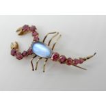 A RUBY AND MOONSTONE SCORPION BROOCH mounted in yellow metal with simple hook fastening. Length 4.