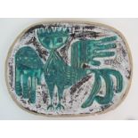 AN OVAL CERAMIC DISH with stylized tubelined decoration of a winged creature in turquoise glaze on a