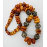 AN AMBER COLOURED BEAD NECKLACE all beads are freeform rounded pebble shapes, interspaced with white