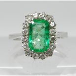 AN 18CT WHITE GOLD EMERALD AND DIAMOND DRESS RING the emerald is a bright mid green, dimensions