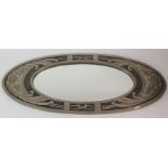 A MARGARET GILMOUR WALL MIRROR of oval shape, the white metal frame decorated with flowerheads and