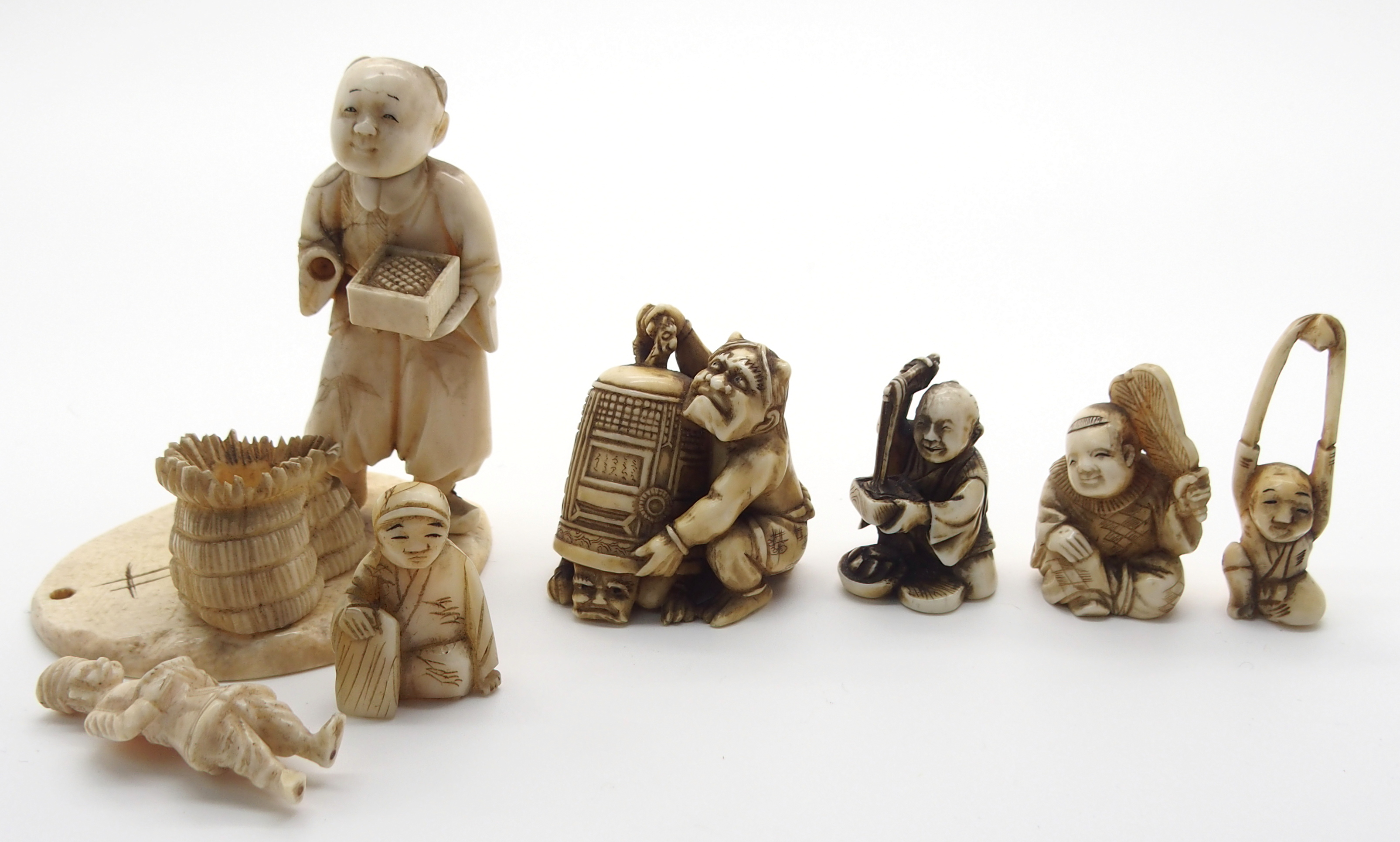 A JAPANESE IVORY OKIMONO ONI holding a temple bell enclosing another demon, 5cm high, a netsuke of a