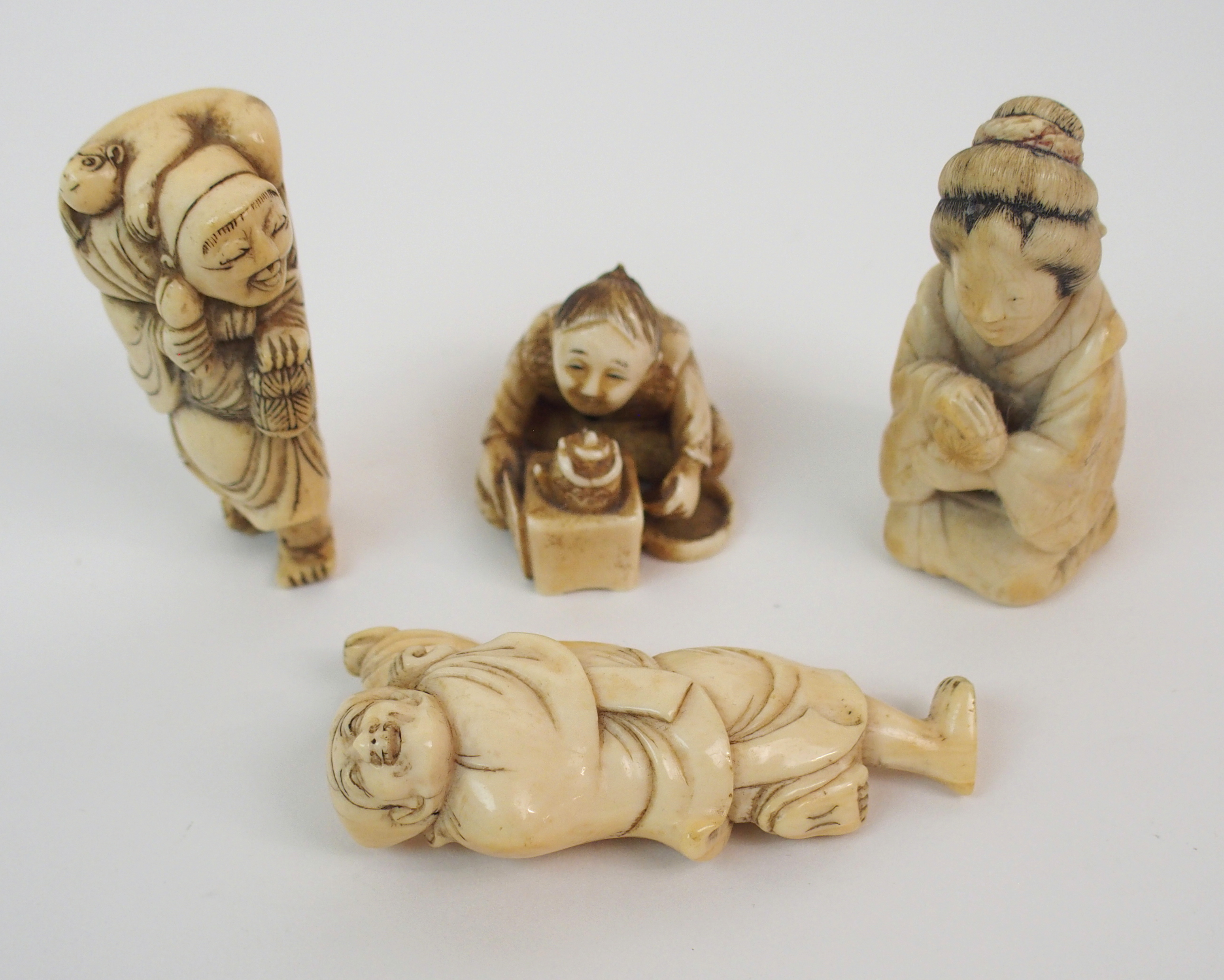 THREE JAPANESE IVORY NETSUKE one with a child seated with a kettle, 3cm high, figure with monkey,