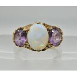 A 9ct gold amethyst and white opal three stone ring with scroll mount. Finger size approx M,