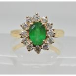 A bright yellow metal emerald and diamond cluster ring, diamonds estimated approx 0.50cts, emerald