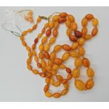 A long string of amber coloured beads, largest bead 23.2mm x 17.1mm, smallest 10mm x 6.9mm, length