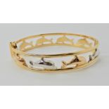 A three colour gold dolphin bangle stamped 750, UAE, inner dimensions 6cm x 5.3cm, weight 15.6gms