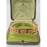 A 9ct gold bangle with a floral theme, hallmarked Birmingham 1884-5, in original box, 1.3cm x 6.7cm,