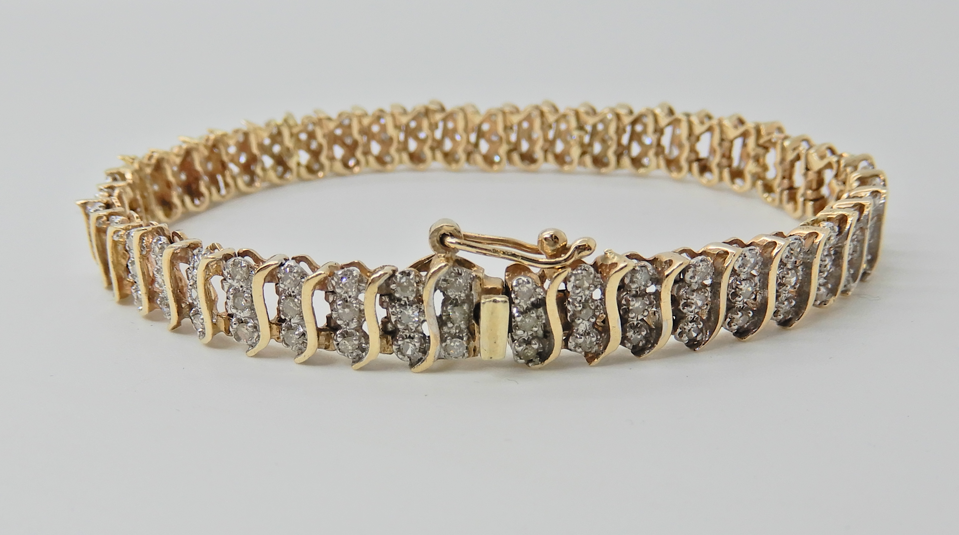 A 9ct gold diamond set bracelet, with 'S' shaped links, stamped 375 and the diamond content is
