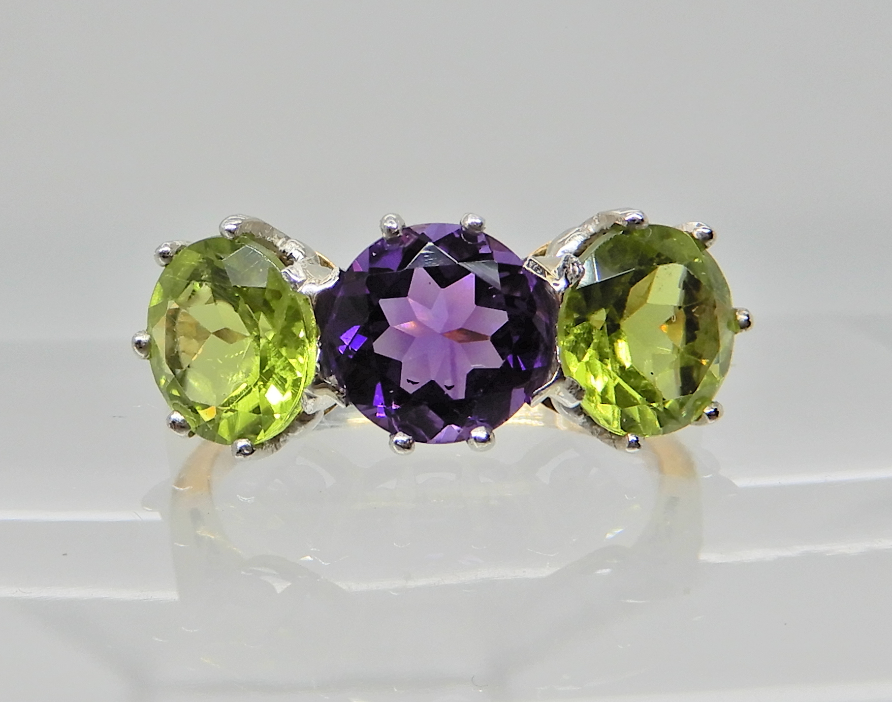 An 18ct gold and platinum peridot and amethyst three stone ring, Finger size N1/2 weight 4.1gms