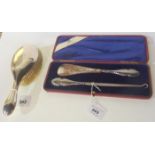 A lot comprising a cased silver handled buttonhook and shoehorn set and a silver mounted brush