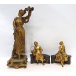 A gilded spelter figure of a woman titled Une Reptiton together with a pair of spelter figures of
