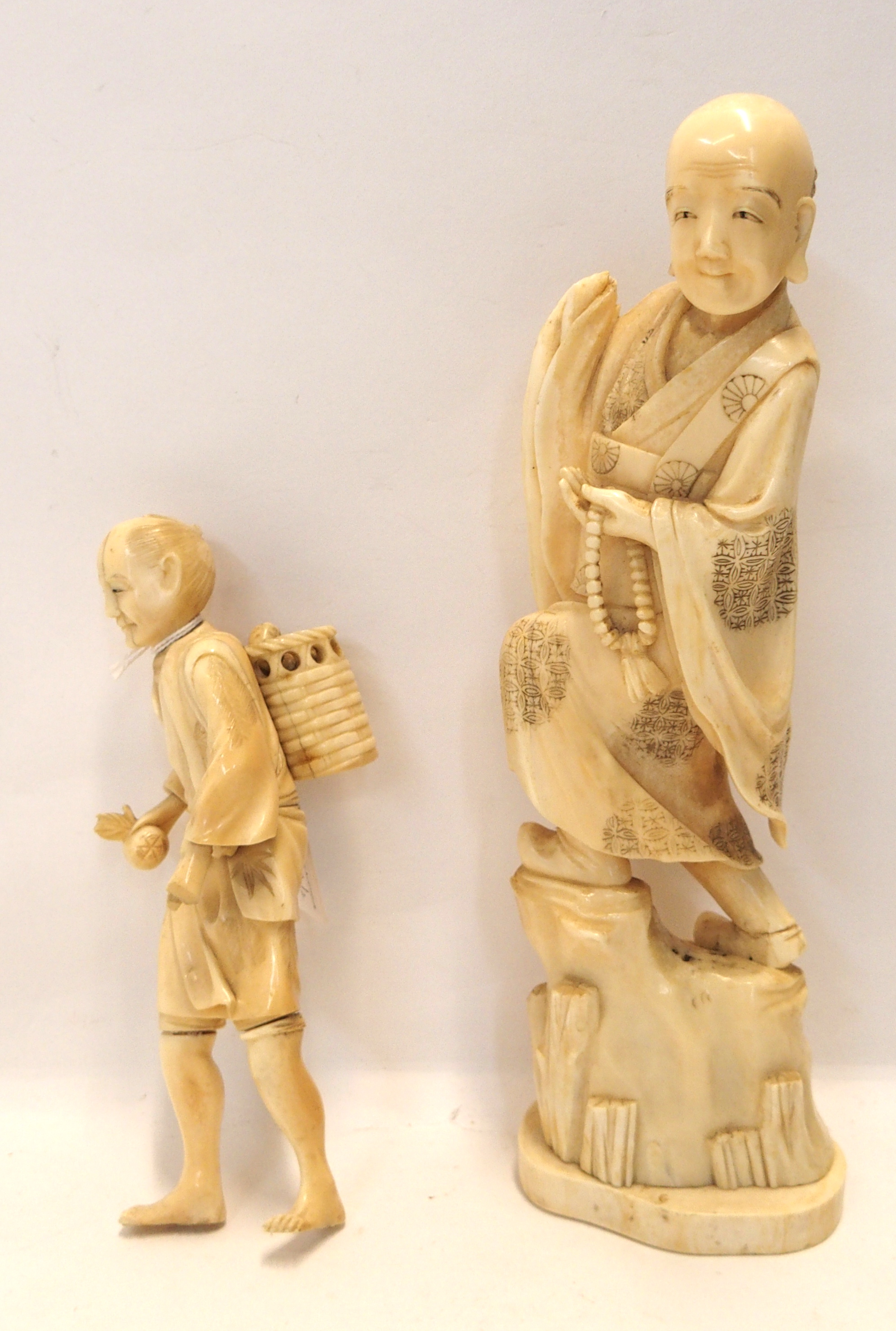 An ivory okimono of a man with a basket on his back and another figure (larger) (2) Gilbert Telfer
