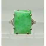 A white metal Chinese green hardstone Art Deco ring with diamond accents to the shoulders