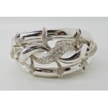 A white metal bangle stamped 750, the floral design set with diamonds weight approx 52.2gms (two