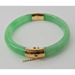 A 14k gold mounted Chinese green hardstone bangle, weight approx 44gms Condition Report:
