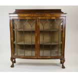 A 1930s walnut veneered bow front display cabinet with two ribbed glazed doors enclosing two lined