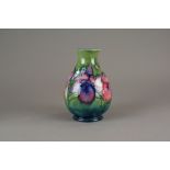 A Moorcroft vase tube lined with Spring Flowers against a green ground,