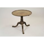 A George III style mahogany tripod table the circular dished top tilt top on a squat column,